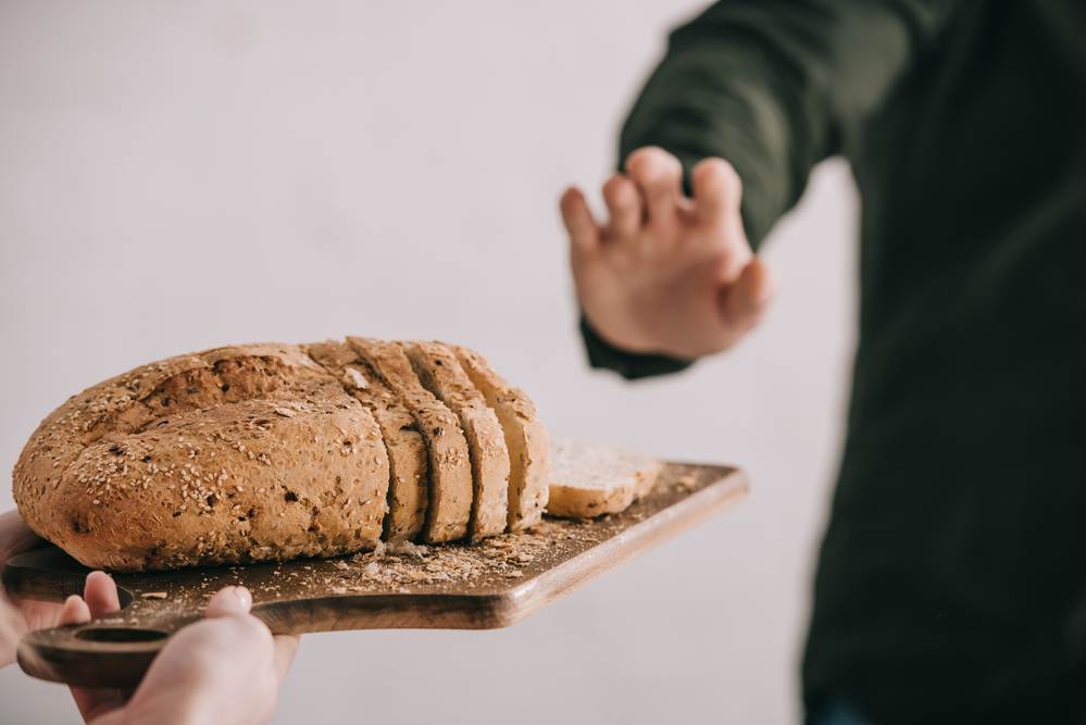 A man turning down gluten-containing bread because of his celiac disease.